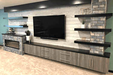 Rustic-modern living room wall with TV and shelves by Lincoln's remodel company Nate's Custom Renvoations